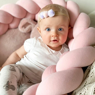 bebe adosse sur tresse de lit rose