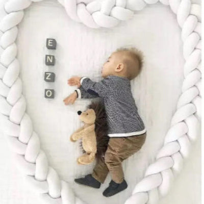 bebe endormi sur le lit au milieu de tresse de lit avec nounours