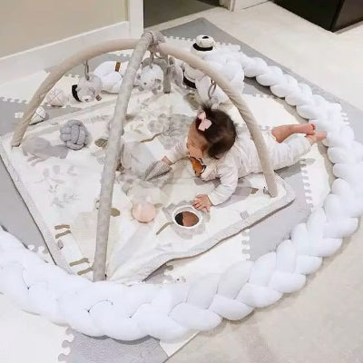 bebe joue sur tapis d eveil au milieu de tresse de lit