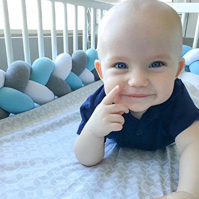 berceau avec tresse de lit bleu blanc gris bebe sourit