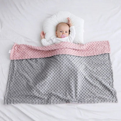 couverture bebe gris rose avec bulles en relief sur enfant allonge