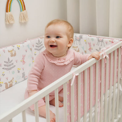 tour de lit bebe souriant assis dans berceau